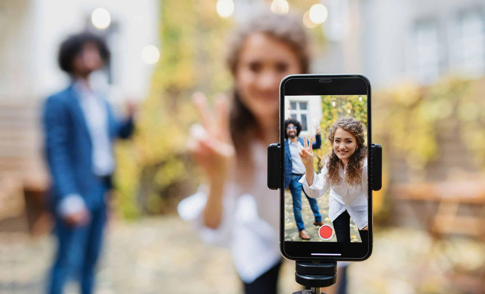 Young couple making video with smartphone outdoors on street, tik tok concept.